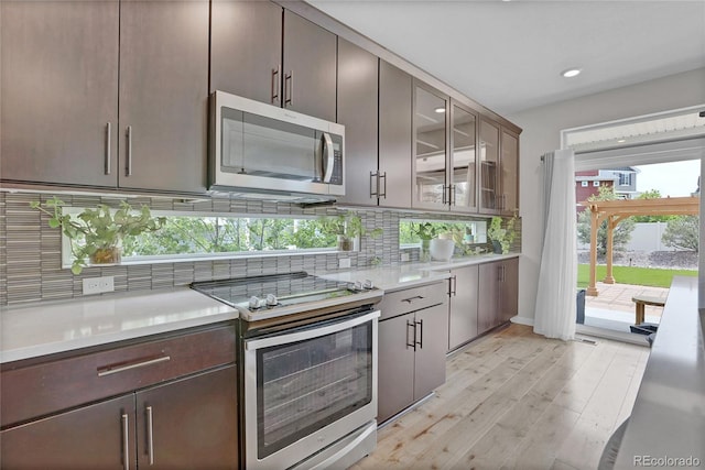 21900 E 46th Pl, Aurora, CO 80019 - kitchen with appliances with stainless steel finishes, light countertops, tasteful backsplash, light wood-style floors, and glass insert cabinets