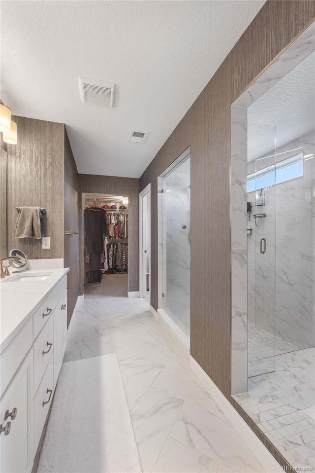 bathroom with vanity, a textured ceiling, a shower with shower door, and wood walls