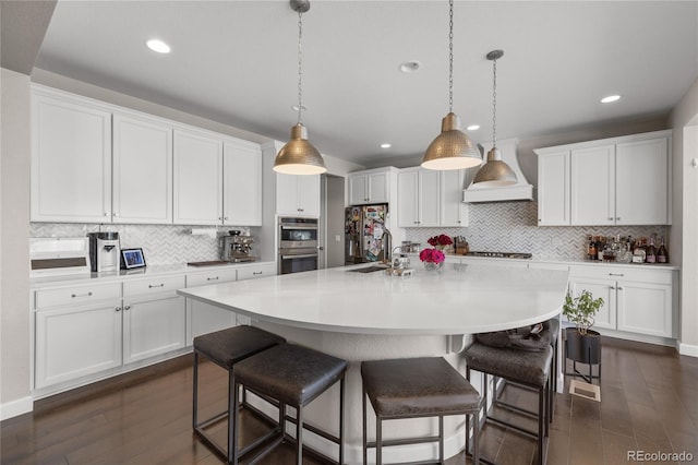 kitchen with white cabinets, decorative light fixtures, and a large island with sink