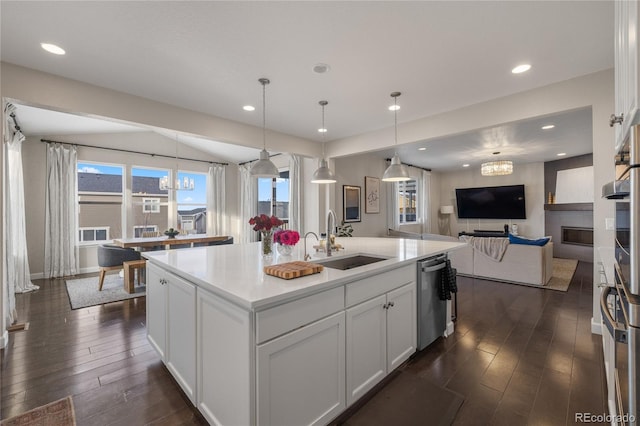 kitchen with dishwasher, decorative light fixtures, a kitchen island with sink, white cabinets, and sink