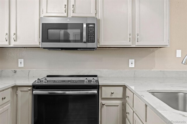 7767 Elmwood St, Littleton, CO 80125 - kitchen with stainless steel appliances, a sink, white cabinetry, and light stone countertops