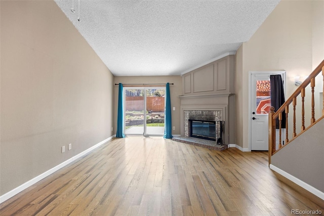 7767 Elmwood St, Littleton, CO 80125 - unfurnished living room with wood finished floors, a textured ceiling, a brick fireplace, stairway, and baseboards