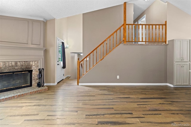 7767 Elmwood St, Littleton, CO 80125 - unfurnished living room featuring wood finished floors, stairway, a textured ceiling, baseboards, and a brick fireplace
