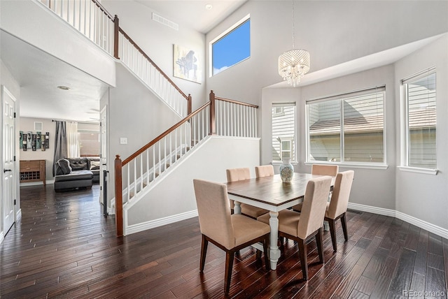 dining space featuring a high ceiling, stairway, baseboards, dark wood-type flooring, and a chandelier