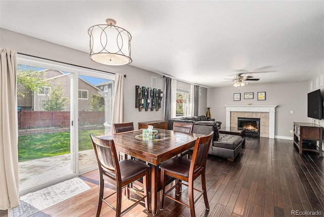 dining area with ceiling fan, dark wood-style floors, and a fireplace