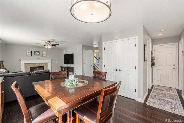 dining area with a ceiling fan, dark wood-style flooring, a tile fireplace, baseboards, and recessed lighting