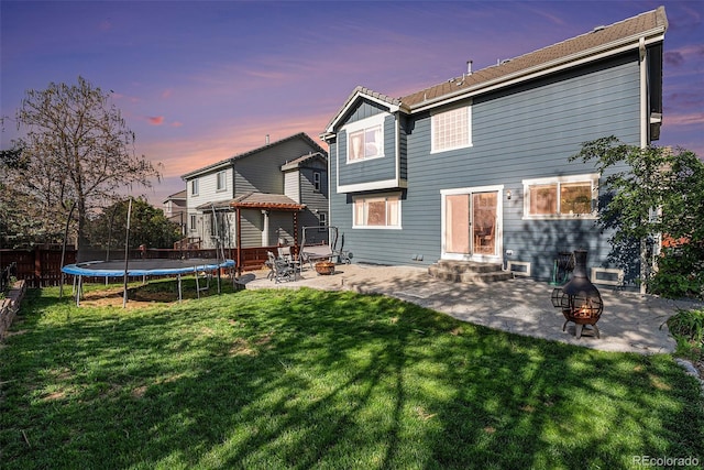 back of house featuring an outdoor fire pit, a trampoline, a patio area, and entry steps