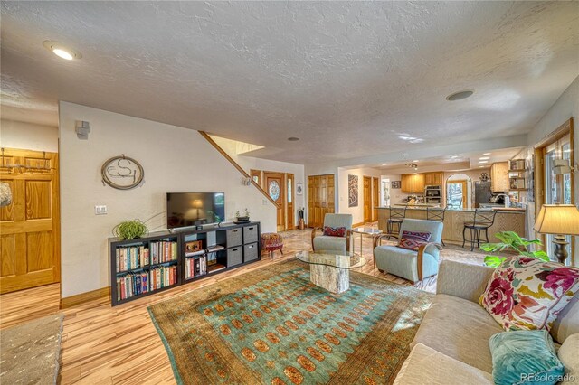 living room featuring light wood-type flooring and a textured ceiling