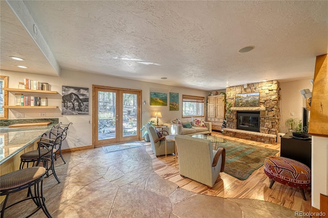 living room with french doors, a textured ceiling, and a stone fireplace