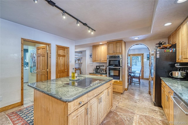 kitchen with a center island, track lighting, dark stone countertops, a textured ceiling, and appliances with stainless steel finishes