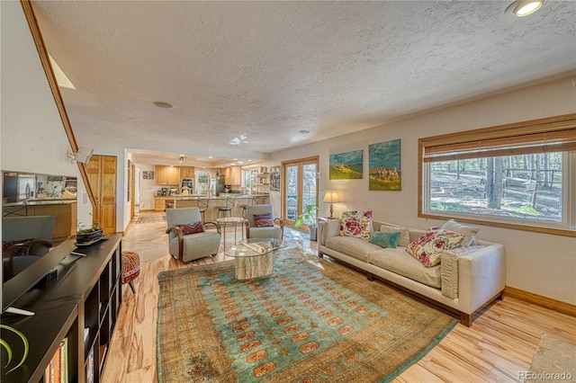 living room with a healthy amount of sunlight, light hardwood / wood-style floors, and a textured ceiling