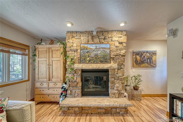 living room featuring a fireplace, a textured ceiling, and light wood-type flooring