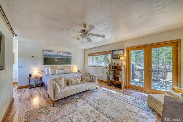 bedroom with french doors, light wood-type flooring, a textured ceiling, access to outside, and ceiling fan