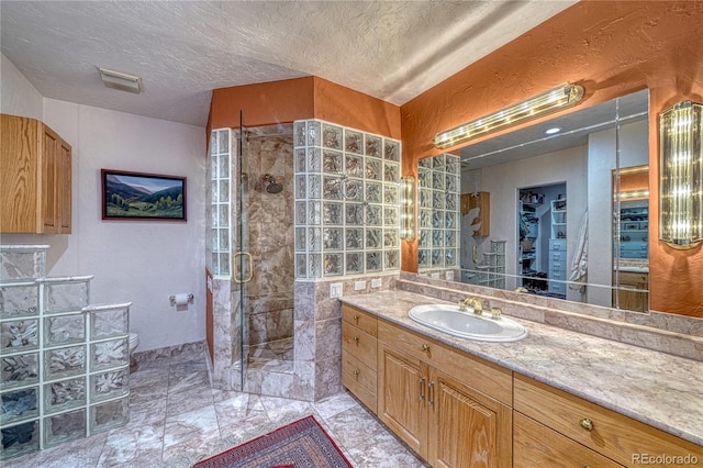 bathroom featuring a textured ceiling, vanity, an enclosed shower, and toilet