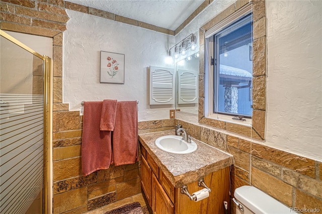 bathroom featuring a textured ceiling, vanity, toilet, and a shower with shower door