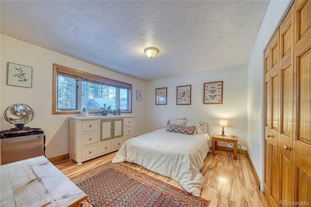 bedroom featuring a closet, a textured ceiling, and light wood-type flooring