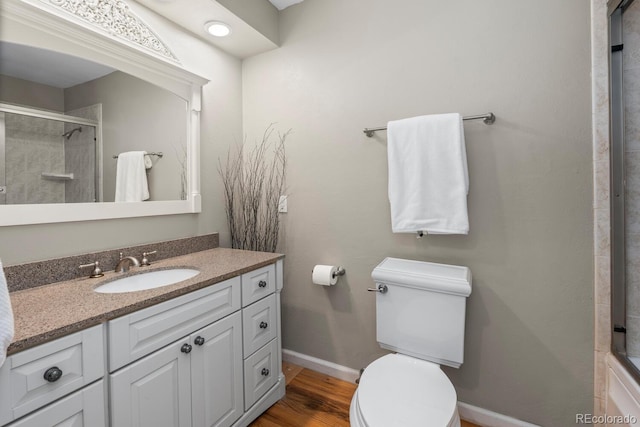 bathroom featuring vanity, a shower with shower door, wood-type flooring, and toilet