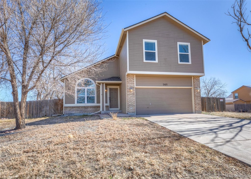 traditional home with a garage, brick siding, concrete driveway, and fence