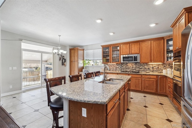 kitchen featuring a center island with sink, a breakfast bar area, a chandelier, pendant lighting, and sink