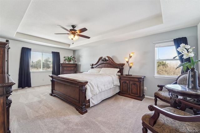 carpeted bedroom with ceiling fan and a tray ceiling