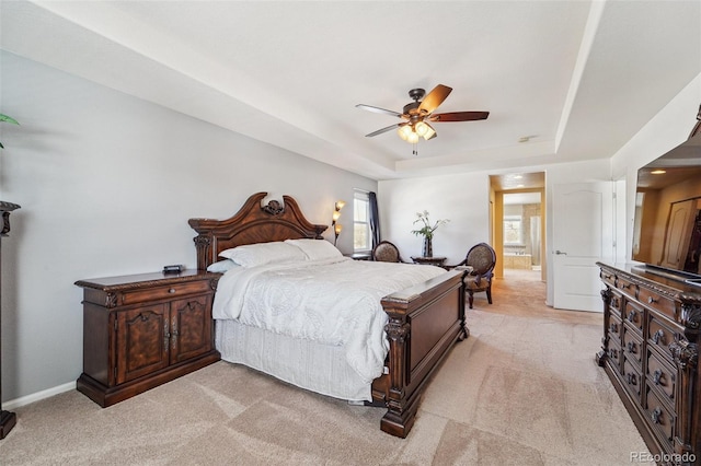 bedroom with light carpet, ceiling fan, and a raised ceiling