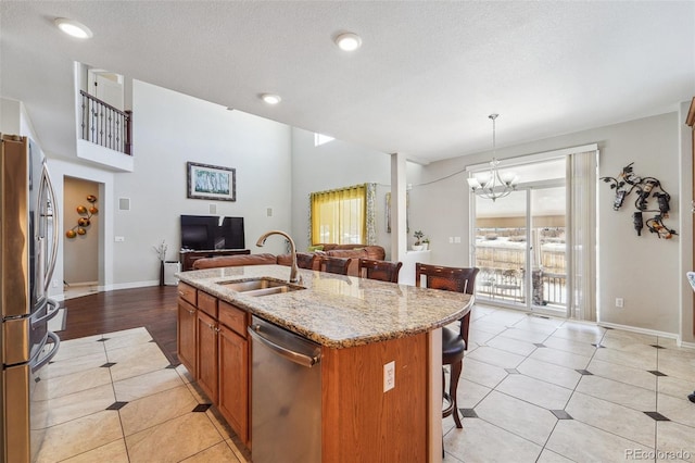 kitchen with a breakfast bar, a kitchen island with sink, a sink, appliances with stainless steel finishes, and open floor plan