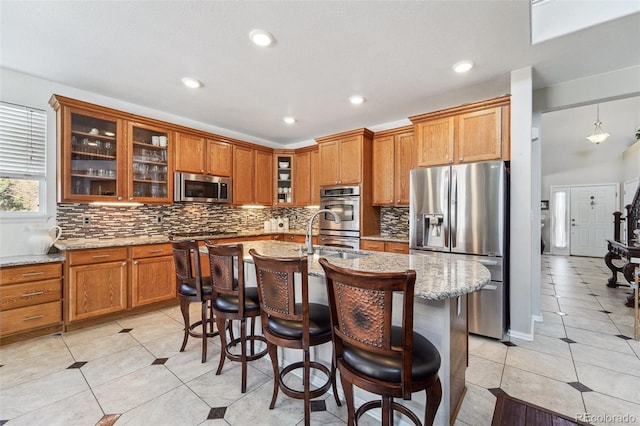 kitchen featuring brown cabinetry, light tile patterned floors, stainless steel appliances, and a sink