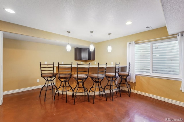 bar with baseboards, visible vents, wet bar, finished concrete floors, and a textured ceiling