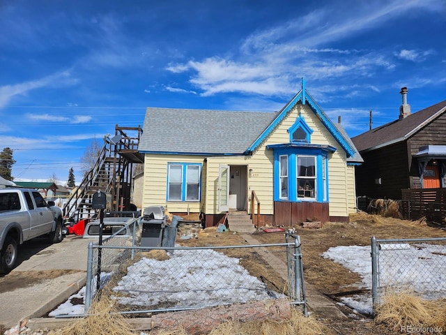 view of front of property with a fenced front yard and a shingled roof