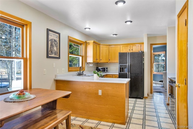 757 Thompson Park Rd, Fairplay, CO 80440 - kitchen featuring black fridge with ice dispenser, stainless steel microwave, a sink, a peninsula, and light countertops