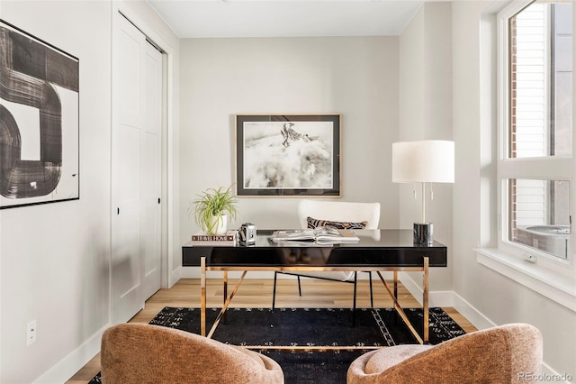 home office featuring baseboards, a healthy amount of sunlight, and wood finished floors