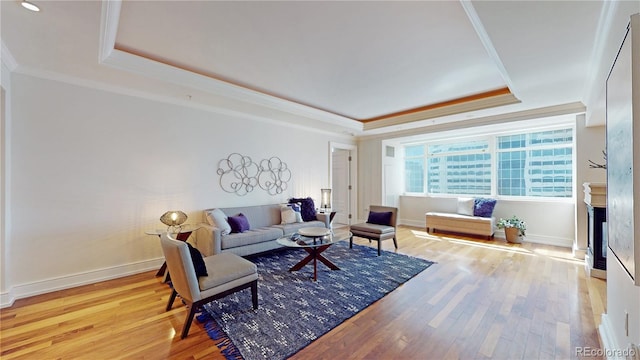 living room featuring light hardwood / wood-style floors, ornamental molding, and a tray ceiling