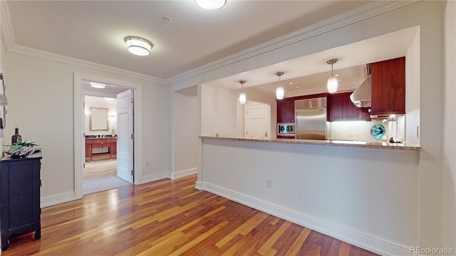 kitchen featuring kitchen peninsula, built in appliances, decorative light fixtures, and light stone countertops