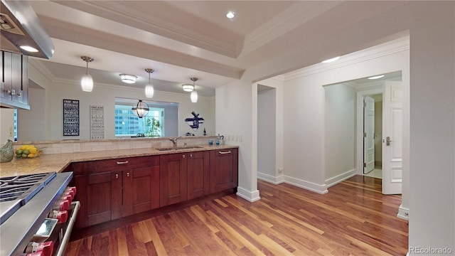 kitchen featuring sink, light hardwood / wood-style flooring, stainless steel range, decorative light fixtures, and light stone counters