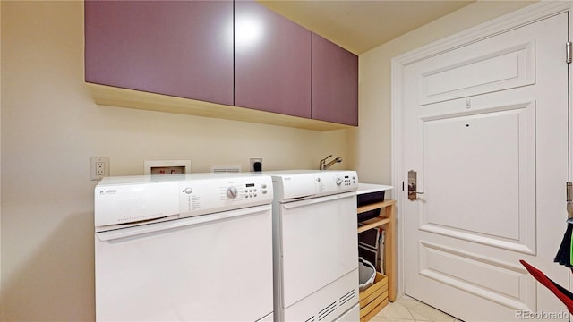 laundry area featuring washer and clothes dryer, light tile patterned flooring, and cabinets