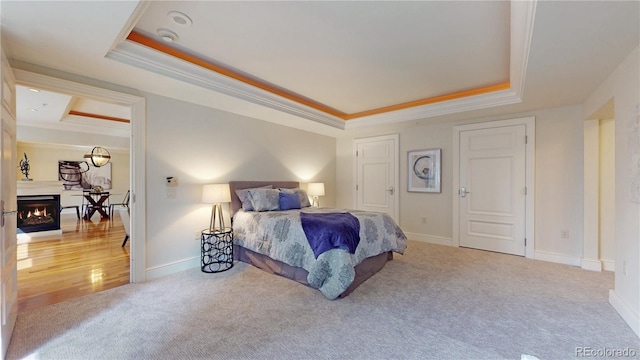 bedroom featuring a raised ceiling, crown molding, and carpet flooring