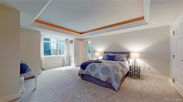 carpeted bedroom with ornamental molding and a tray ceiling