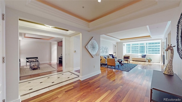 hall with a raised ceiling, ornamental molding, and hardwood / wood-style flooring