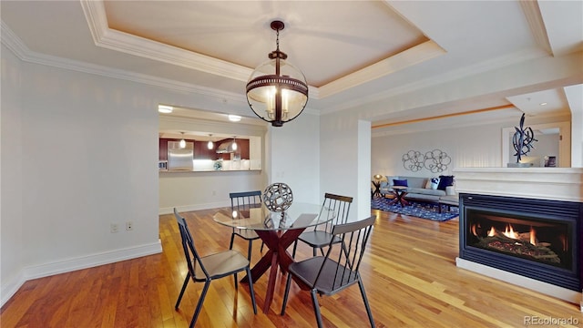 1891 Curtis St Unit 1613, Denver, CO 80202 - dining space featuring a tray ceiling, wood finished floors, ornamental molding, a lit fireplace, and a chandelier