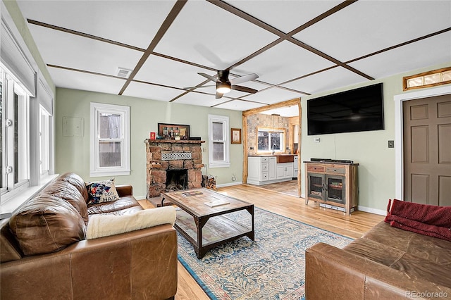 124 River Dr, Bailey, CO 80421 - living area featuring a ceiling fan, light wood finished floors, a stone fireplace, and baseboards