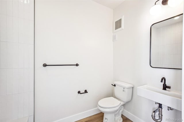 bathroom featuring baseboards, visible vents, toilet, wood finished floors, and a sink