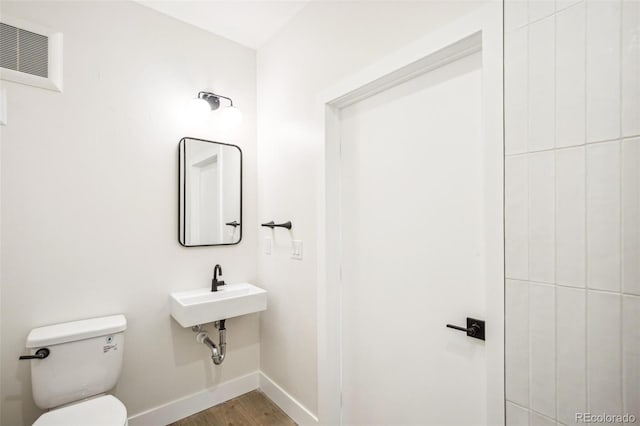 bathroom with toilet, baseboards, visible vents, and wood finished floors