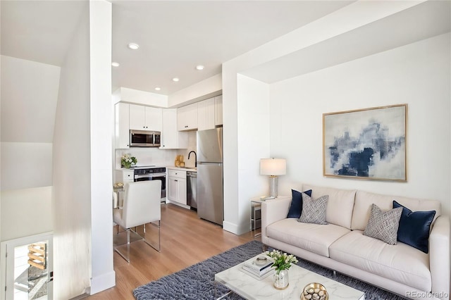 living room featuring recessed lighting, light wood-style flooring, and baseboards