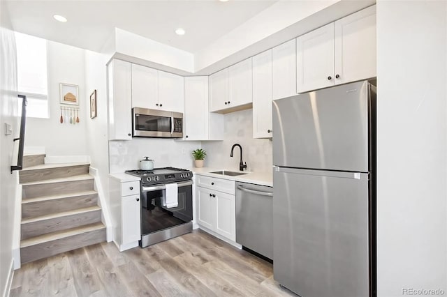 kitchen with white cabinetry, stainless steel appliances, a sink, and light countertops