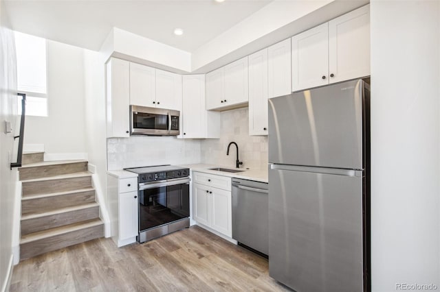 kitchen featuring white cabinets, appliances with stainless steel finishes, backsplash, and a sink