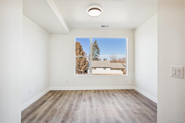 spare room featuring visible vents, baseboards, and wood finished floors