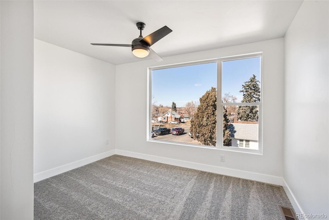 carpeted spare room featuring plenty of natural light, visible vents, and baseboards