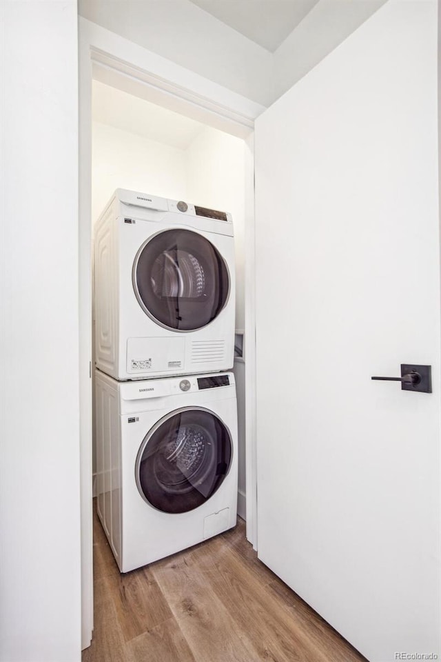 laundry area with laundry area, stacked washing maching and dryer, and wood finished floors