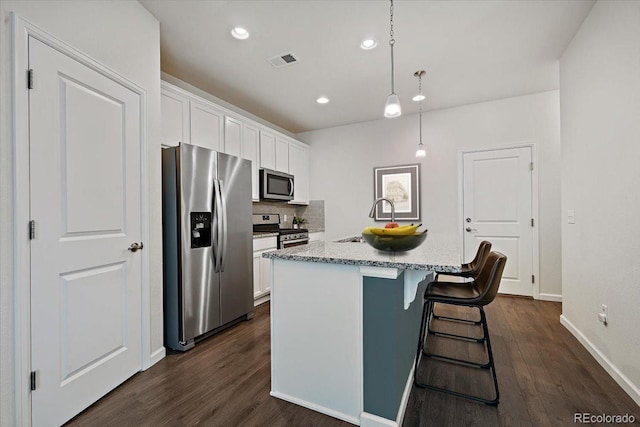 kitchen with stainless steel appliances, hanging light fixtures, a center island with sink, and white cabinets