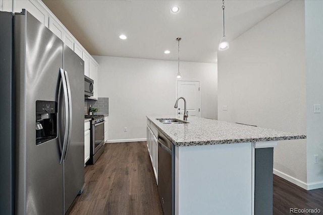 kitchen featuring sink, white cabinetry, decorative light fixtures, appliances with stainless steel finishes, and a kitchen island with sink